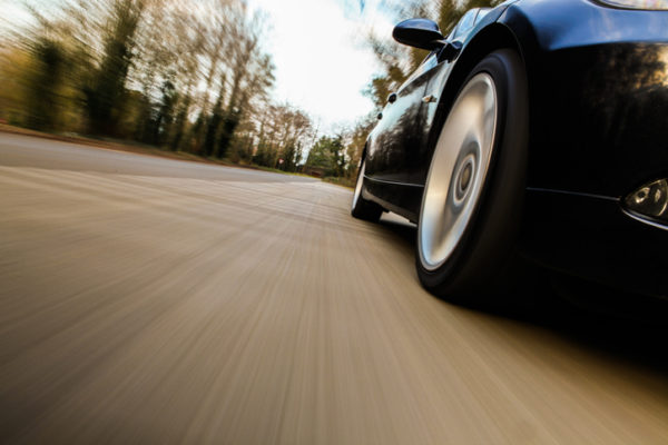 A low angle view of a car speeding down a rural road