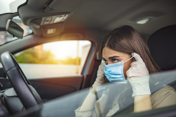 Woman puts on a facemask preparing to drive