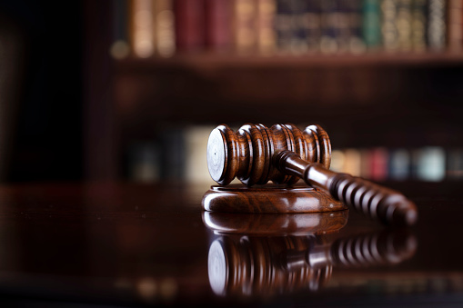 Judge‘s gavel on brown shining table and bookshelf background.