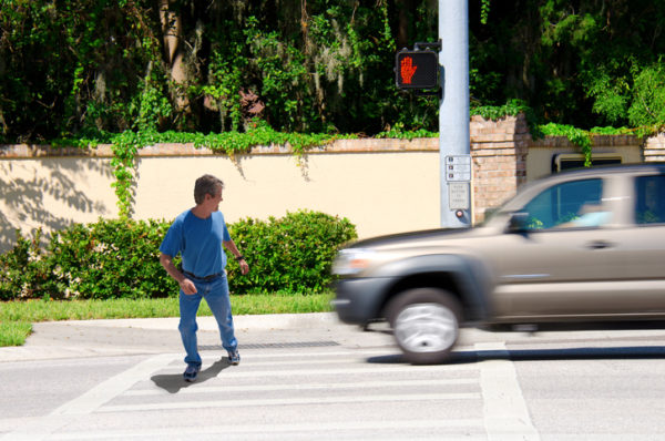 A man narrowly avoids getting hit by an SUV while going through a crosswalk.